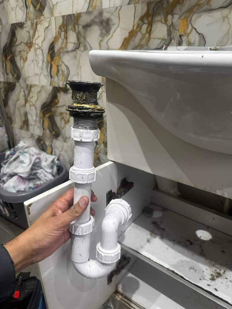 Clogged bathroom sink drain pipe with repair work in progress.